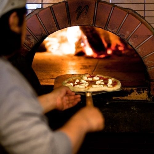Chef, Alberto Ilescas, putting a pizza in the wood fired oven at Bentwood Tavern in New Buffalo, Michigan.