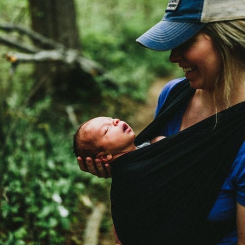 A young woman holding her newborn baby's face to the sky in Warren Woods State Park, Michigan.