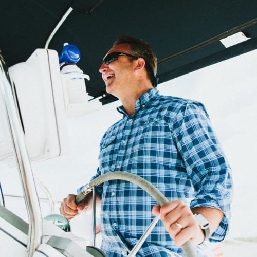 A passenger taking a turn at the helm of New Buffalo Sailing Excursions on Lake Michigan.