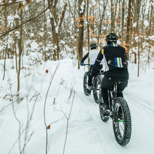 Riding fat tire bikes downhill through a snowy forest at Love Creek County Park in southwest Michigan.