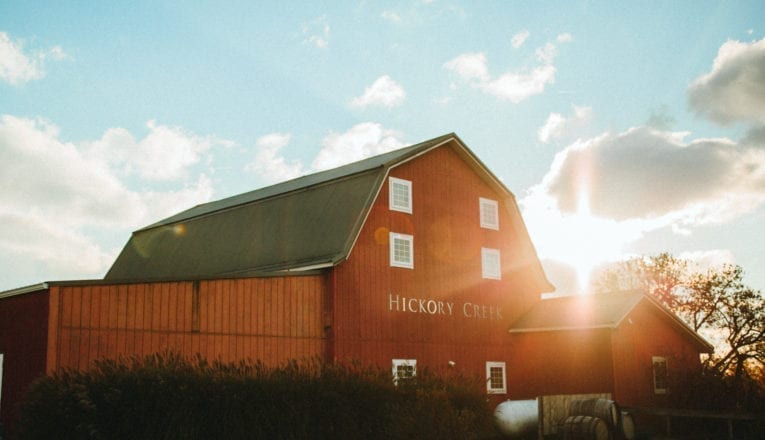 Early evening sun peeks over Hickory Creek Winery's red barn tasting room.