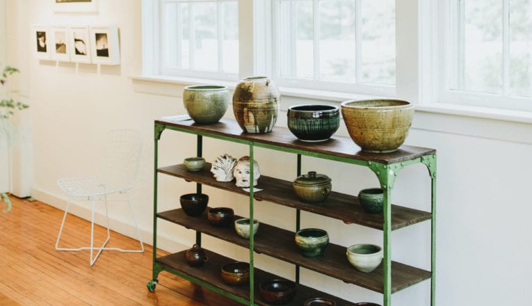 Vintage ceramics on an old green bakers rack with contemporary art in the light-filled gallery space at Judith Racht Gallery in Harbert, Michigan.