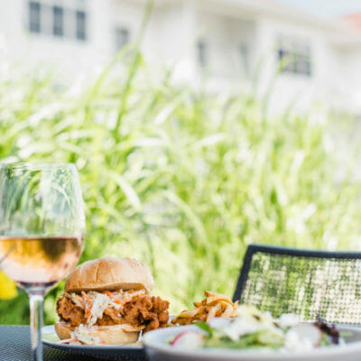 Spicy Korean fried chicken sandwich and a glass of wine on the waterfront patio at Bentwood Tavern in New Buffalo, Michigan.