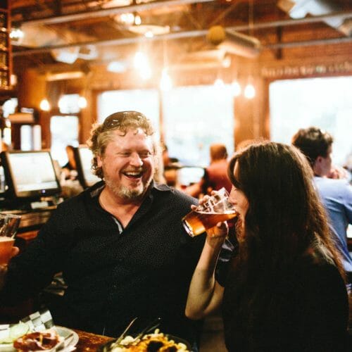 A couple laughing and drinking at Greenbush Brewing in Sawyer, Michigan.