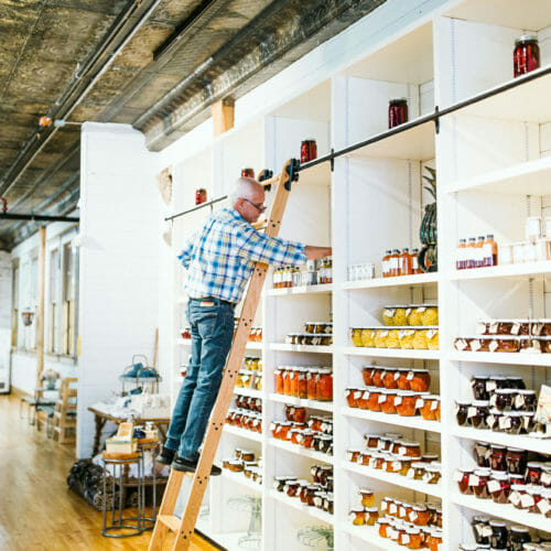 A man stocking preserves on a library ladder at Froehlich's in Three Oaks, Michigan.