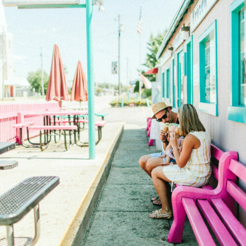 A young couple sitting on a pink bench outside Oink's Dutch Treat in New Buffalo, Michigan.