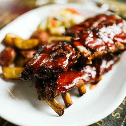 A plate of juicy ribs with shimmering barbecue sauce at Red Arrow Roadhouse in Union Pier, Michigan
