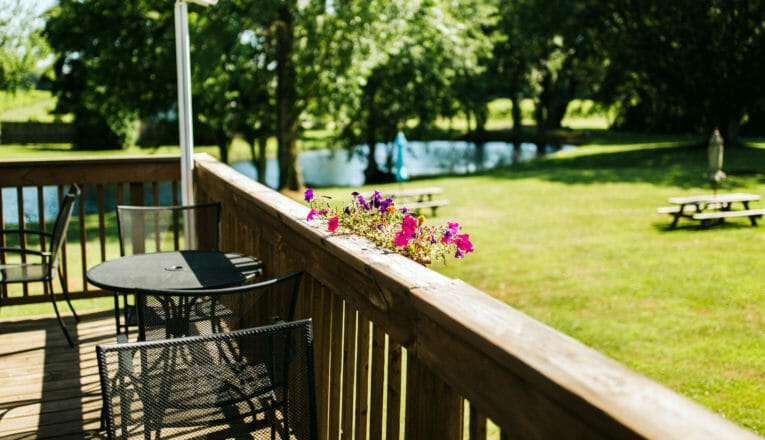 A wood deck overlooking a grassy picnic area and pond at Domain Berrien in Berrien Springs, Michigan.