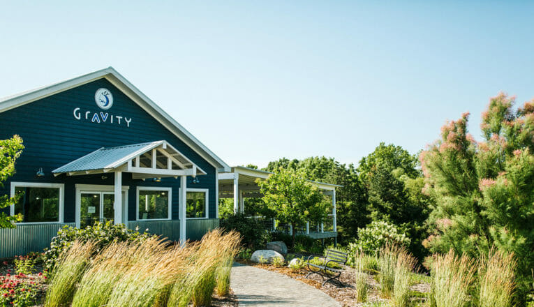 View of Gravity Vineyards and Winery's tasting room with with lush green landscaping in Baroda, Michigan.
