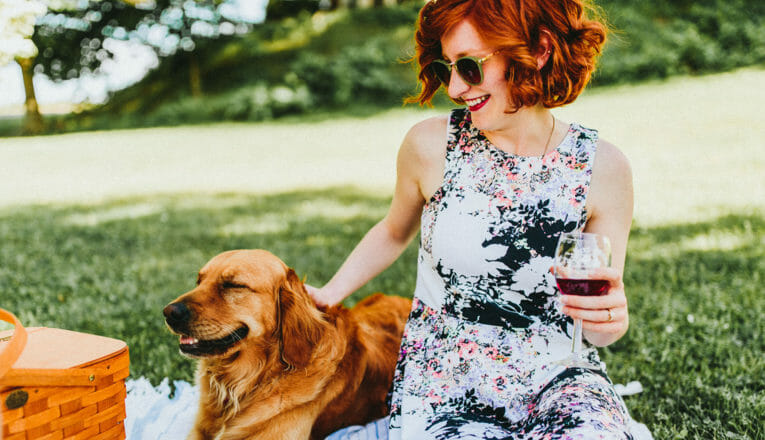 A young woman picnicking with a happy golden retriever at Lemon Creek Winery in Berrien Springs, Michigan.