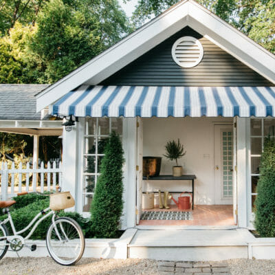 Cottage exterior with striped blue awning, pink tile and classic beach cruiser bicycle at The Leo Cottage in Union Pier, Michigan.