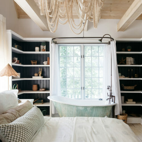 Master bedroom with built-in shelving and a vintage clawfoot tub at The Leo Cottage in Union Pier, Michigan.
