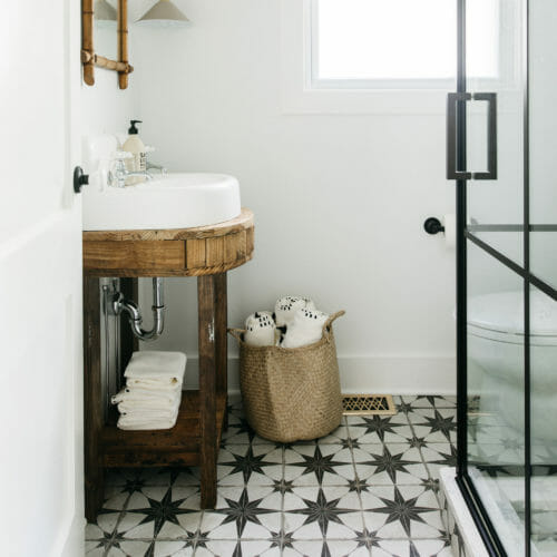 Bath with Atlas tile floor and glass-walled standup shower at The Leo Cottage in New Buffalo, Michigan.