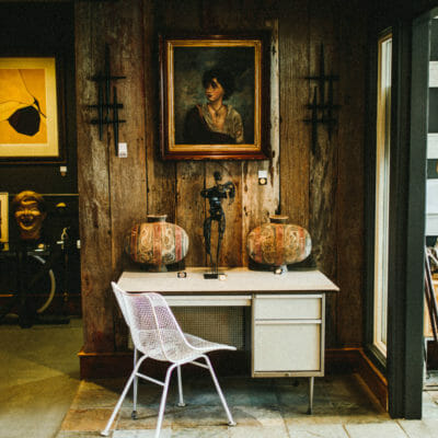 A vintage portrait hung over a modern white desk and chair at Alchemy Antiques in Harbert, Michigan.