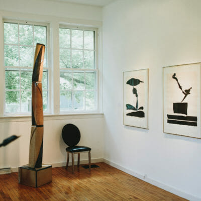 Graphic black and white prints and a tall organic wooden sculpture at Judith Racht Gallery in Harbert, Michigan.
