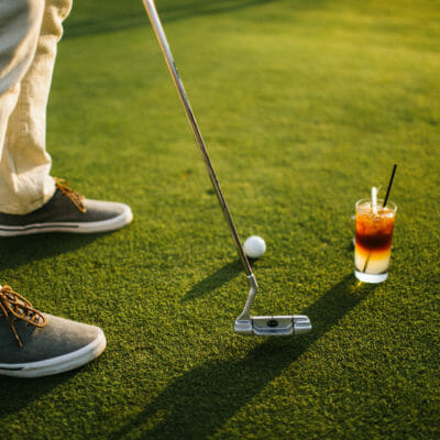 detailed image of tennis shoes a putter and golf ball and a cocktail