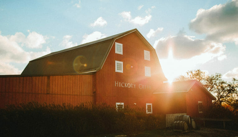 A stately red barn with the sun setting behind it at Hickory Creek Winery in Buchanan, Michigan.