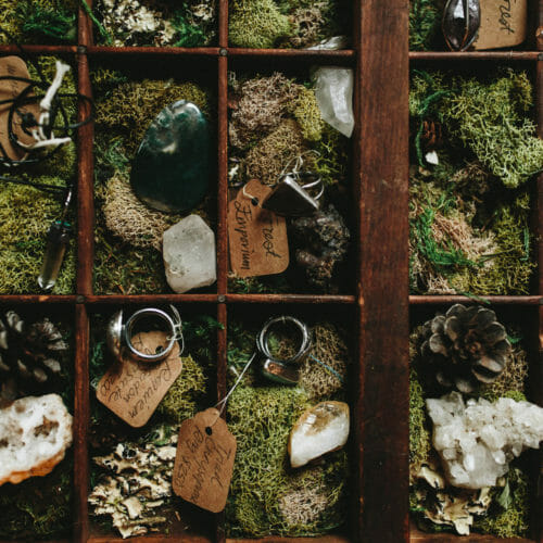 Handcrafted jewelry beautifully displayed with moss and pine cones at Journeyman Artisan Market in Three Oaks, Michigan.