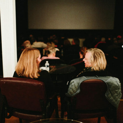 Two friends chatting in the lounge area at Vickers Theatre in Three Oaks, Michigan.