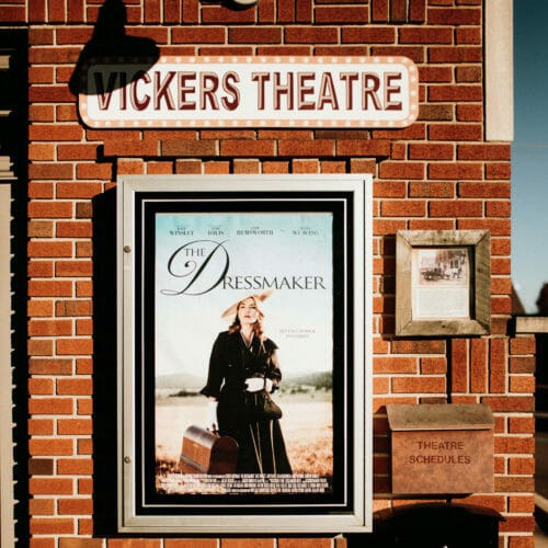 A movie poster and hand-painted sign on a brick wall at the entry to Vickers Theatre in Three Oaks, Michigan.