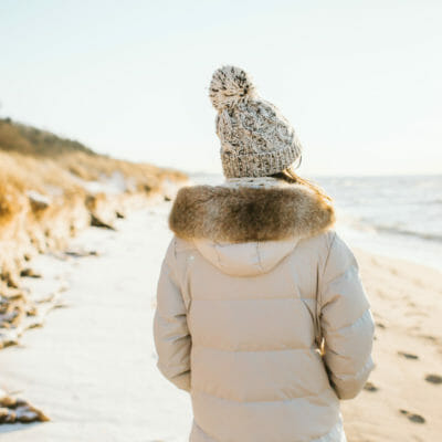 Woman in white parka and warm hat on the beach at Warren Dunes in Sawyer, Michigan.