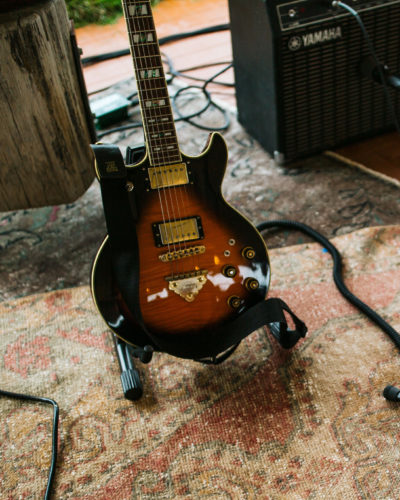 A brown and amber electric guitar sitting on a vintage rug at River Saint Joe in Buchanan, Michigan.