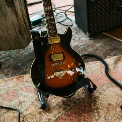 A brown and amber electric guitar sitting on a vintage rug at River Saint Joe in Buchanan, Michigan.