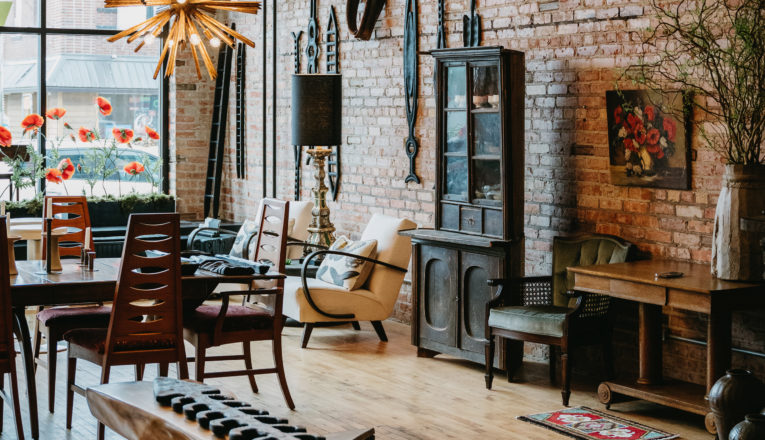 Vintage, antique, and contemporary furnishings displayed in a brick showroom with large front windows at Window Shopping in Sawyer, Michigan.