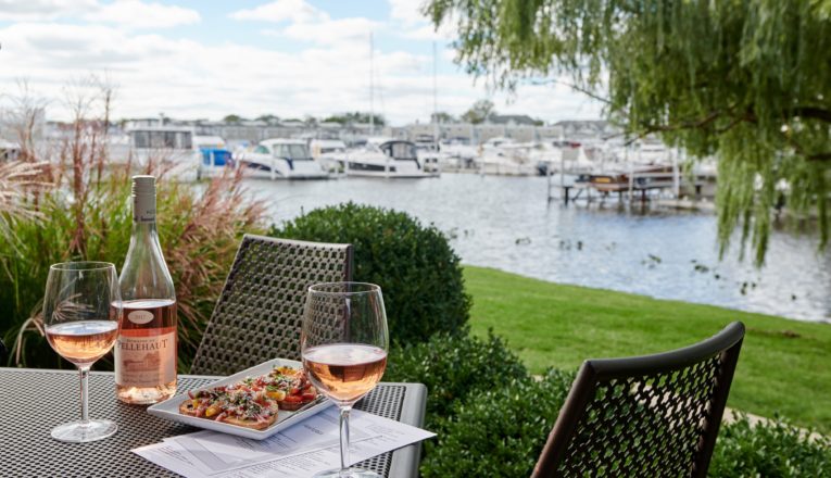 Rose and bruschetta on a metal table with New Buffalo Harbor in the background at Terrace Room.