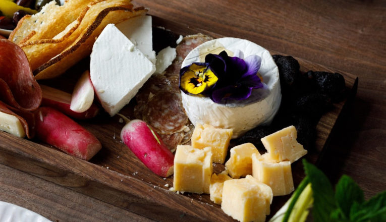 A wood board with various cheese, charcuterie and vegetables from Elderslie Farm.