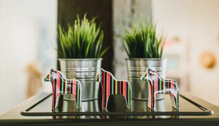 Colorful Scandinavian horses displayed in front of potted grasses at Stockholm Objects in Harbert, Michigan.