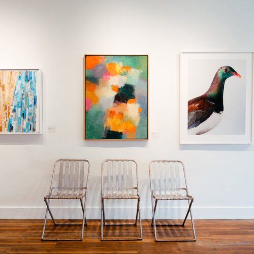 Four colorful paintings and seating on display in a gallery during Art Attack in New Buffalo, Michigan.
