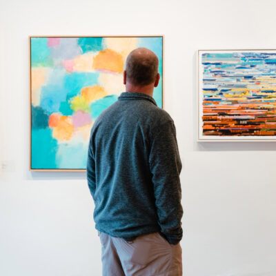 A man gazes at three paintings on a gallery wall during Art Attack in New Buffalo, Michigan.