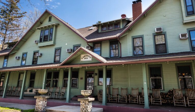 Lakeside Inn's classic green facade with a long row of rocking chairs on the front porch.