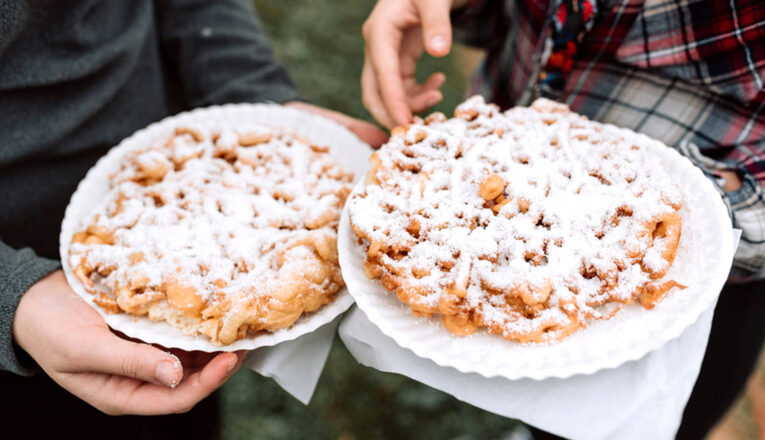 Funnel cakes with powdered sugar on paper plates.
