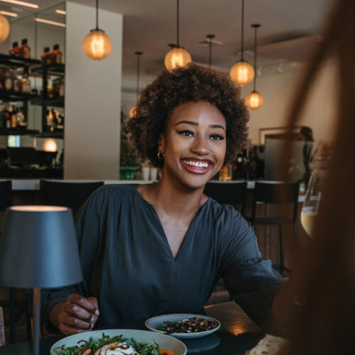 A woman smiles and enjoys a meal and company at Gather in Harbert, Michigan.