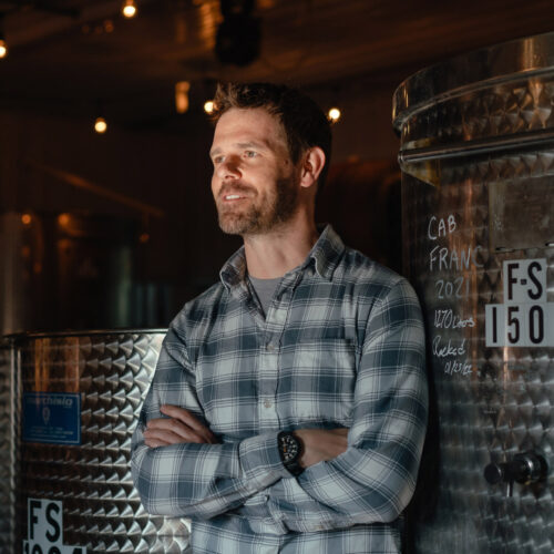 Owner and winemaker Adam McBride standing in front of metal wine barrels at Hickory Creek Winery in Buchanan, Michigan.