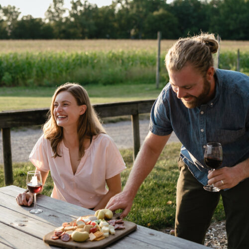 A man and woman enjoy a picnic of cheese, charcuterie, and wine at Hickory Creek Winery in Buchanan, Michigan.