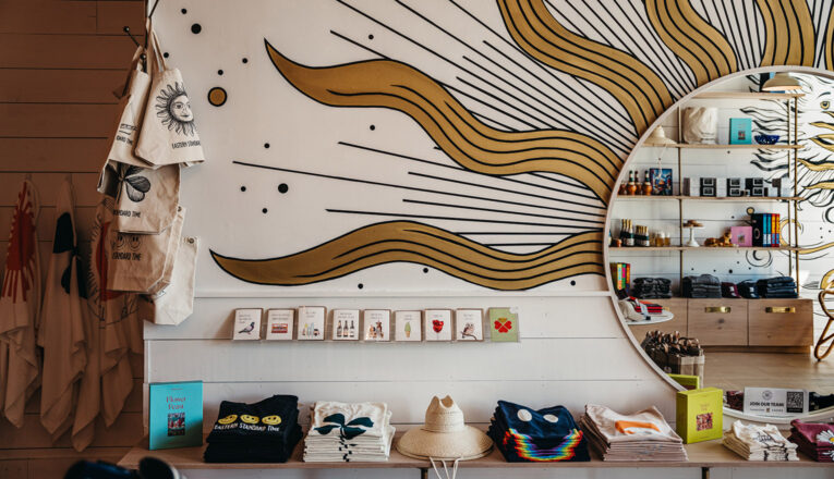 A sunny mural surrounds a round mirror at Eastern Standard Time in New Buffalo, Michigan.