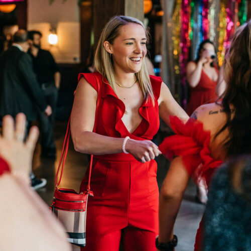 A woman in a red jumpsuit greets a friend at the Harbor Country Pride Prom event in Union Pier, Michigan.