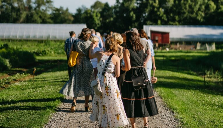 A group of people in summer clothes taking a tour before dinner at Granor Farm in Three Oaks, Michigan.
