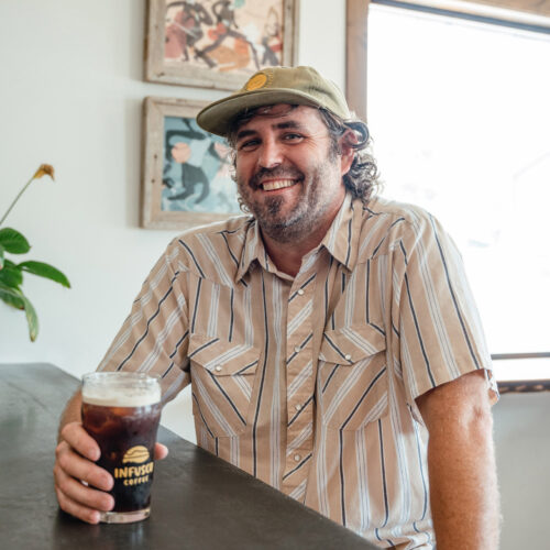 A man smiles while enjoying a Nitro Cold Brew at the bar at Infusco Coffee Roasters in Sawyer, Michigan.