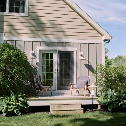 The back porch with chairs surrounded by thoughtful landscaping at Wandering Soul Cabin in Sawyer, Michigan.
