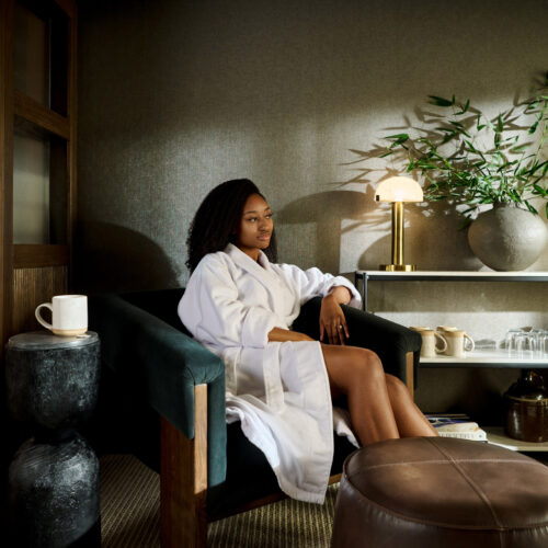 A woman lounging in a bathrobe with a cup of tea at Foundation Spa in New Buffalo, Michigan.