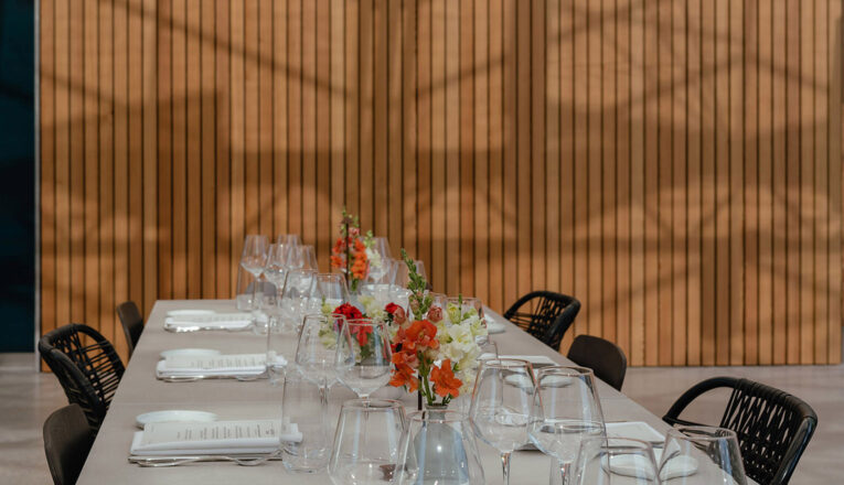A long white table with woven black chairs set with flowers at Granor Farm in Three Oaks, Michigan.