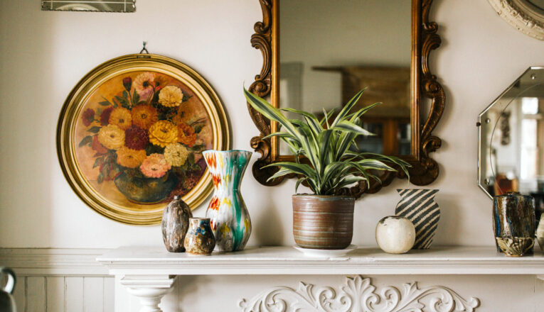 Vintage ceramics, mirrors, and paintings styled above a white fireplace mantle at Mazet in Three Oaks, Michigan.