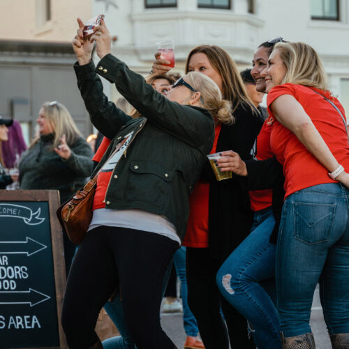 A group of women smiling and taking selfies at New Buffalo Harvest and Wine Festival.
