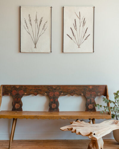 Two botanical canvases hang over a wood bench at Window Shopping in Sawyer, Michigan.