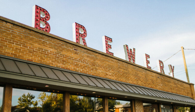 A brick exterior with large windows and letters that spell 'brewery' on the roof at Greenbush Brewing Co. in Sawyer, Michigan.