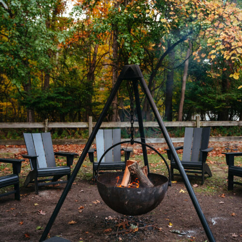 An outdoor firepit surrounded by chairs on an autumn day at The Neighborhood Hotel in New Buffalo, Michigan.